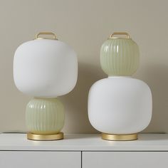 two green and white vases sitting on top of a dresser