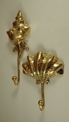 two gold flower shaped hooks on a white wall