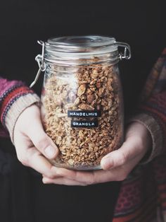 a person holding a jar filled with granola