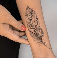 two women with tattoos on their arms holding onto each other's wrist and one has a feather tattoo on it