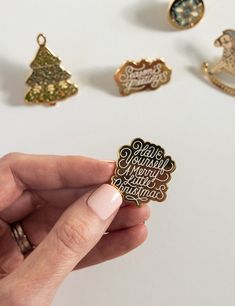 a person holding a small brooch in their left hand and several other pins on the table