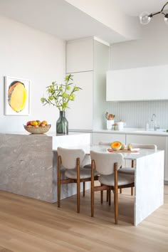 a kitchen with white walls and wooden floors has a marble island in front of the counter