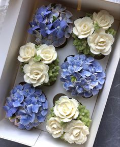 cupcakes with blue and white flowers in a box