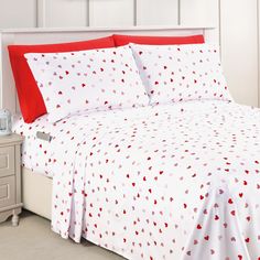 a bed with red and white hearts printed on the sheets, along with two nightstands