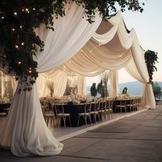 an outdoor wedding setup with white drapes and lights