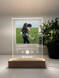 a wooden stand with an image of two people on it and a plant in the background