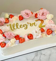 a white cake with strawberries and flowers on it that says regora 2 in gold lettering