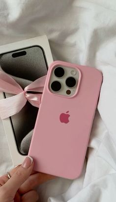 someone is holding their pink iphone case in front of an empty white box with a pink ribbon