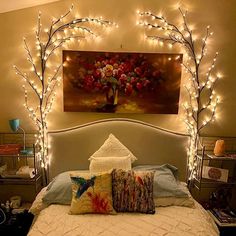 a bed with white sheets and lights on the headboard, in front of a painting