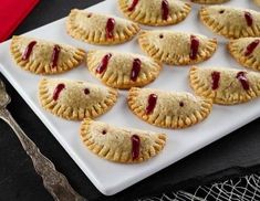 small pastries with jelly filling on a white plate next to silverware and forks