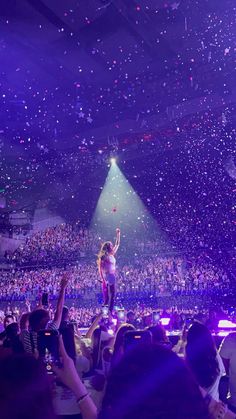 a woman standing on top of a stage surrounded by confetti thrown in the air