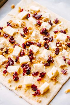 a flatbread topped with cheese and cranberries on top of a baking sheet