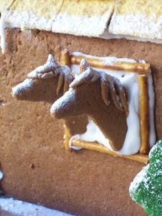 a gingerbread house decorated with icing and a horse head on the front door