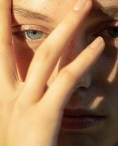 a close up of a person holding their hands to their face with the sun shining on them