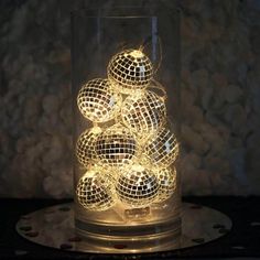 a glass vase filled with disco balls sitting on top of a black tablecloth covered surface