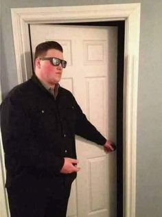 a man standing in front of a door with sunglasses on and pointing to the side