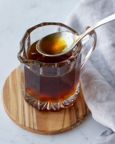 a glass pitcher filled with liquid sitting on top of a cutting board next to a spoon