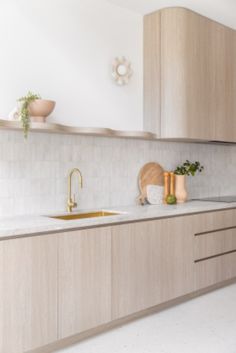 a kitchen with wooden cabinets and marble counter tops, gold faucets and vases on the wall