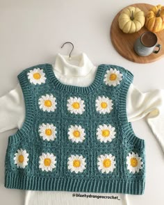 a knitted sweater with white and yellow flowers on it