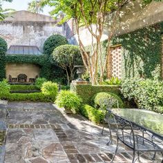 an outdoor patio with tables and chairs surrounded by greenery on either side of the building