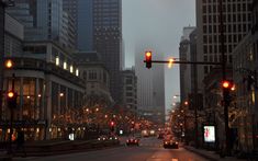 a city street with traffic lights and buildings in the background at night, as seen from across the street