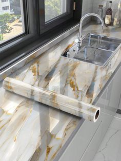 a marble counter top next to a window with a sink and faucet in it