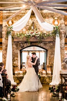 a bride and groom kissing in front of an open fire place at their wedding ceremony