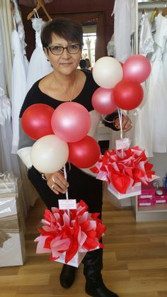 a woman is holding some red and white balloons