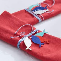 two red napkins with blue and white fish on them, tied to each other