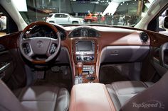 the interior of a car with brown leather seats and steering wheel, on display at an auto show