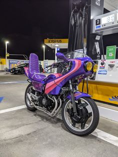 a purple and pink motorcycle parked in front of a gas station