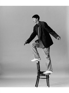 black and white photograph of a man jumping on a chair with one foot in the air