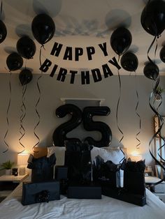 black balloons are hanging from the ceiling in front of a birthday sign and number 25