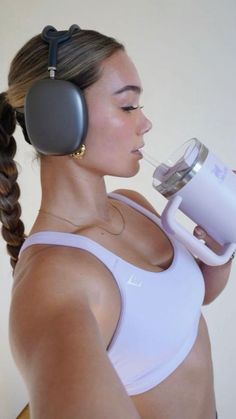 a woman wearing headphones drinking from a cup