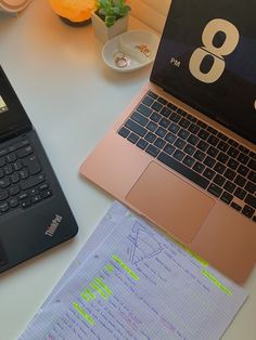 two laptops sitting on top of a table next to each other with papers in front of them