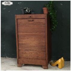 a wooden cabinet sitting next to a pair of yellow shoes