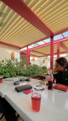 a woman sitting at a table with drinks and cell phones