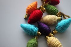 multicolored balls of yarn are arranged in a circle on a gold - plated chain