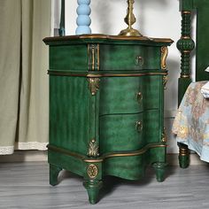 a green dresser sitting on top of a wooden floor next to a bed and nightstand