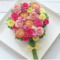 a bouquet of colorful flowers sitting on top of a white square plate with yellow ribbon