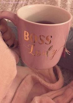 a pink coffee mug with the words boss lady printed on it sitting on a blanket