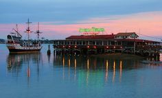 a boat docked at a pier with a restaurant on it's roof in the background