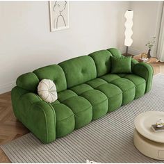 a green couch sitting on top of a wooden floor next to a white coffee table