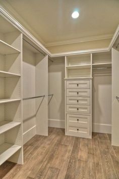 an empty walk in closet with lots of shelves and drawers on the wall, along with wooden flooring