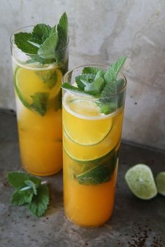 two glasses filled with lemonade, lime and mint