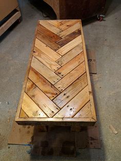 a wooden bench sitting on top of a floor next to a box filled with wood