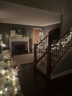 a christmas tree is lit up in the living room with stairs leading to the front door