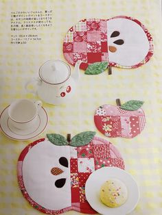 the table is set with plates, cups and an apple shaped placemat on it