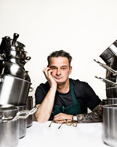 a man sitting at a table surrounded by pots and pans