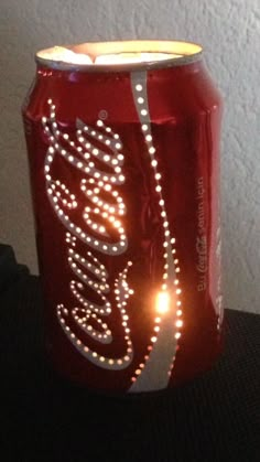 a coca - cola can with some lights on it's side, sitting on a table